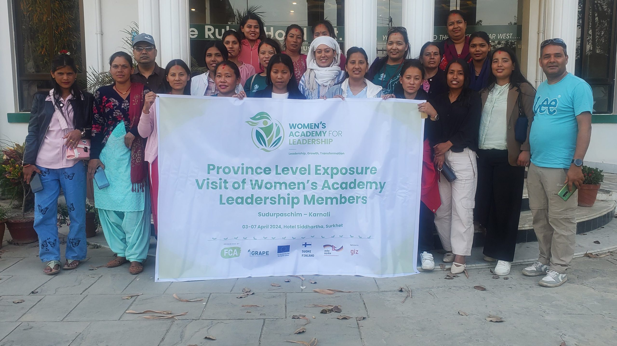 A group of people stand outside a building, posing for a photo and holding a large banner which reads: "WOMEN'S ACADEMY FOR LEADERSHIP. Province Level Exposure Visit of Women's Academy Leadership Members/Sudurpaschim - Karnali"