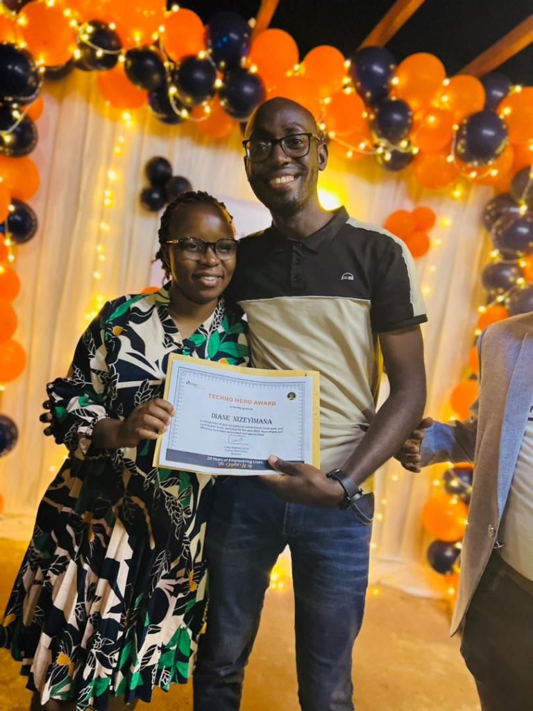 A woman and a man pose for a photo. They are holding a certificate, which bears the women's name - Diane Nizeyimana