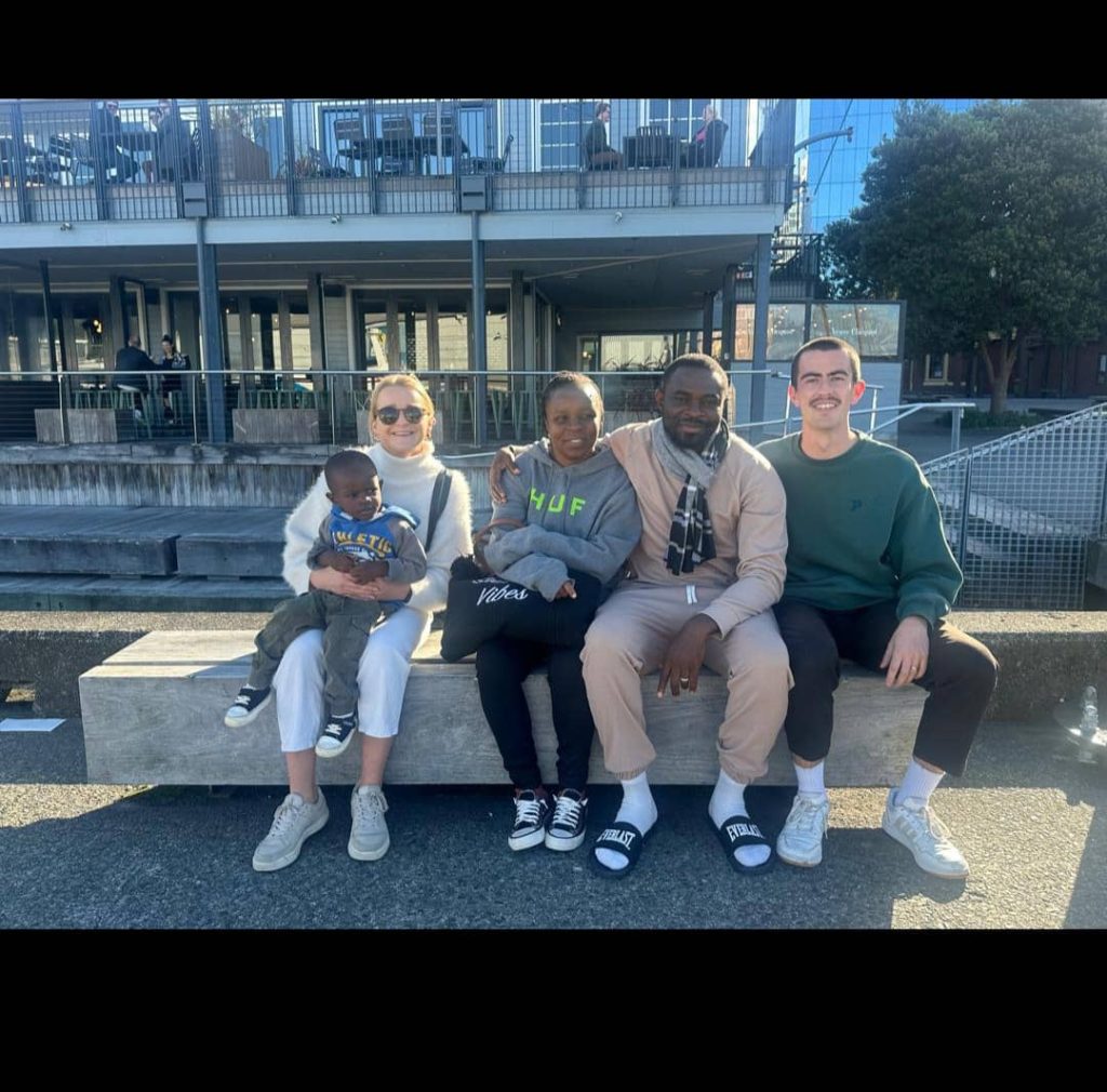 Three grown-ups and a child sit on a bench outside