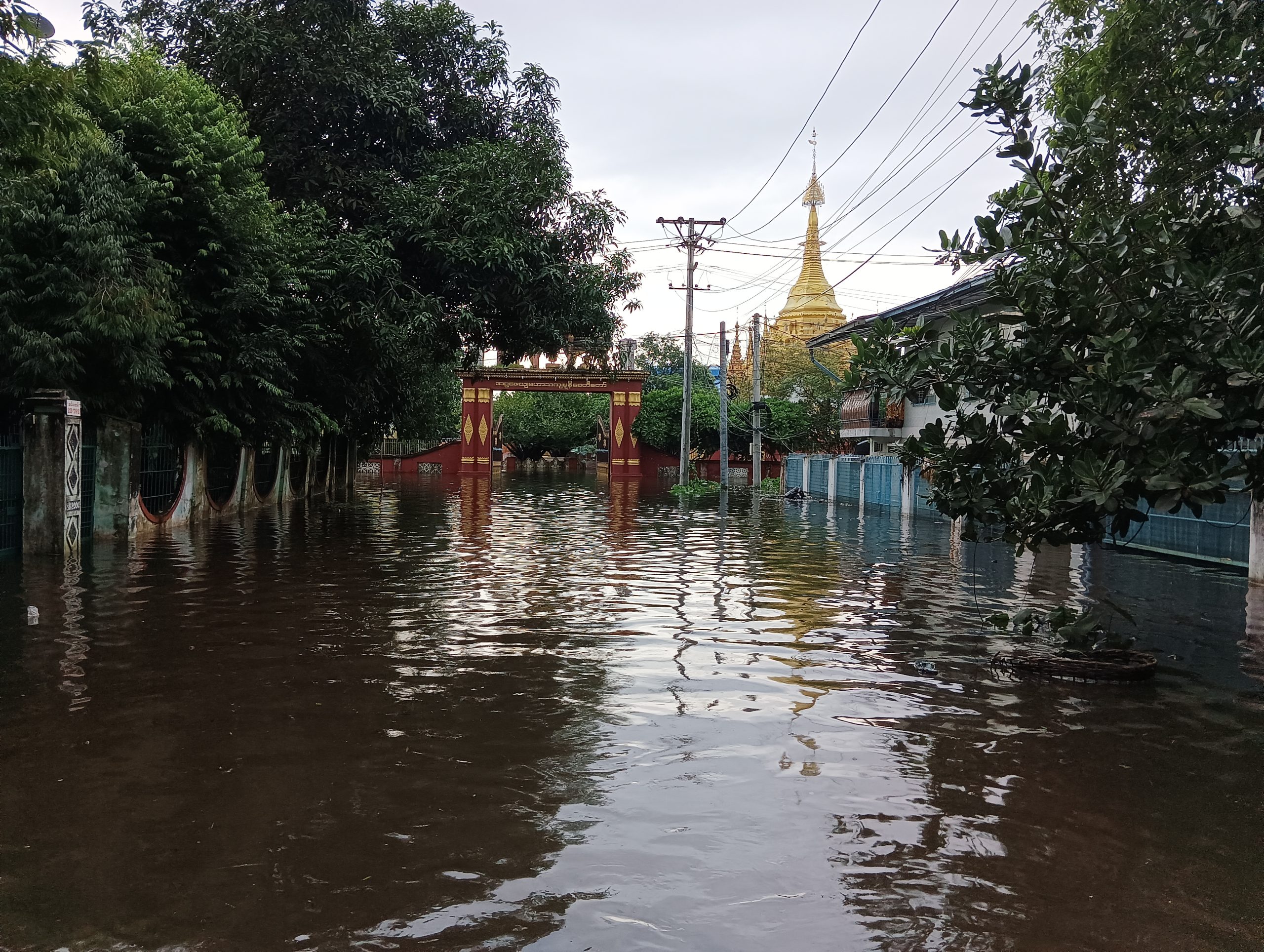 A flooded street showing an ornamental arch half covered in water and the top of a temple