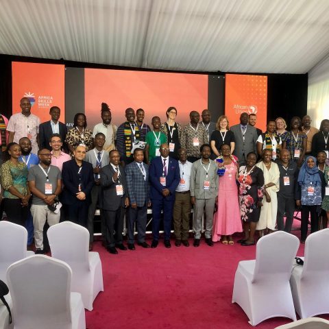 A group of people pose for a formal photo in front of an orange backdrop that bears the logos of Africa Skills Week and the African Union