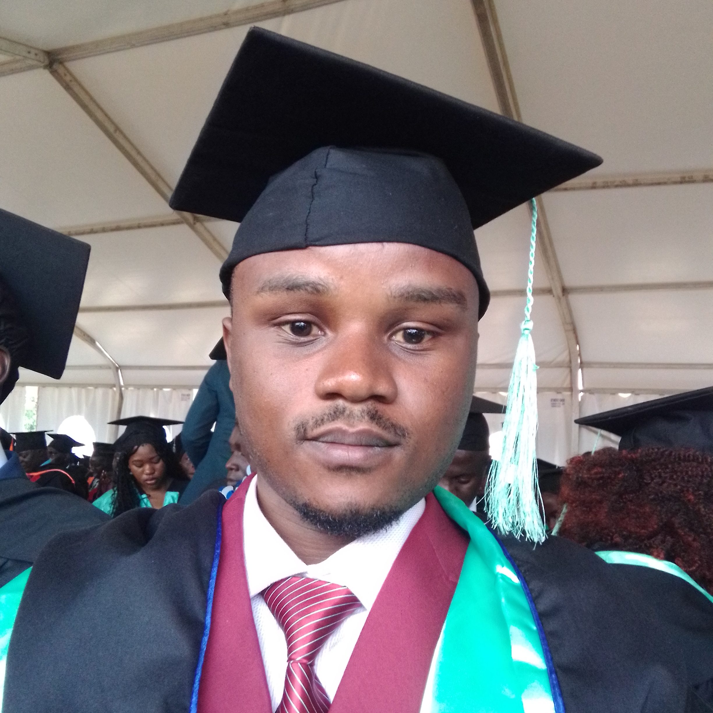 A man in a graduation gown and cap poses for a photograph.