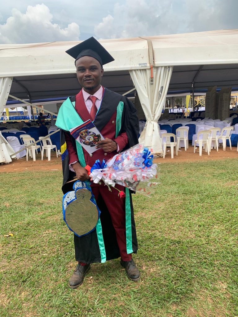 A man in a graduation gown and cap poses for a photograph.