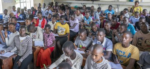 A crowded classroom is full of children sitting at desks