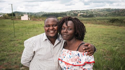 A man and a woman standing next to each other on a slope outside. The man has his arm around the woman.